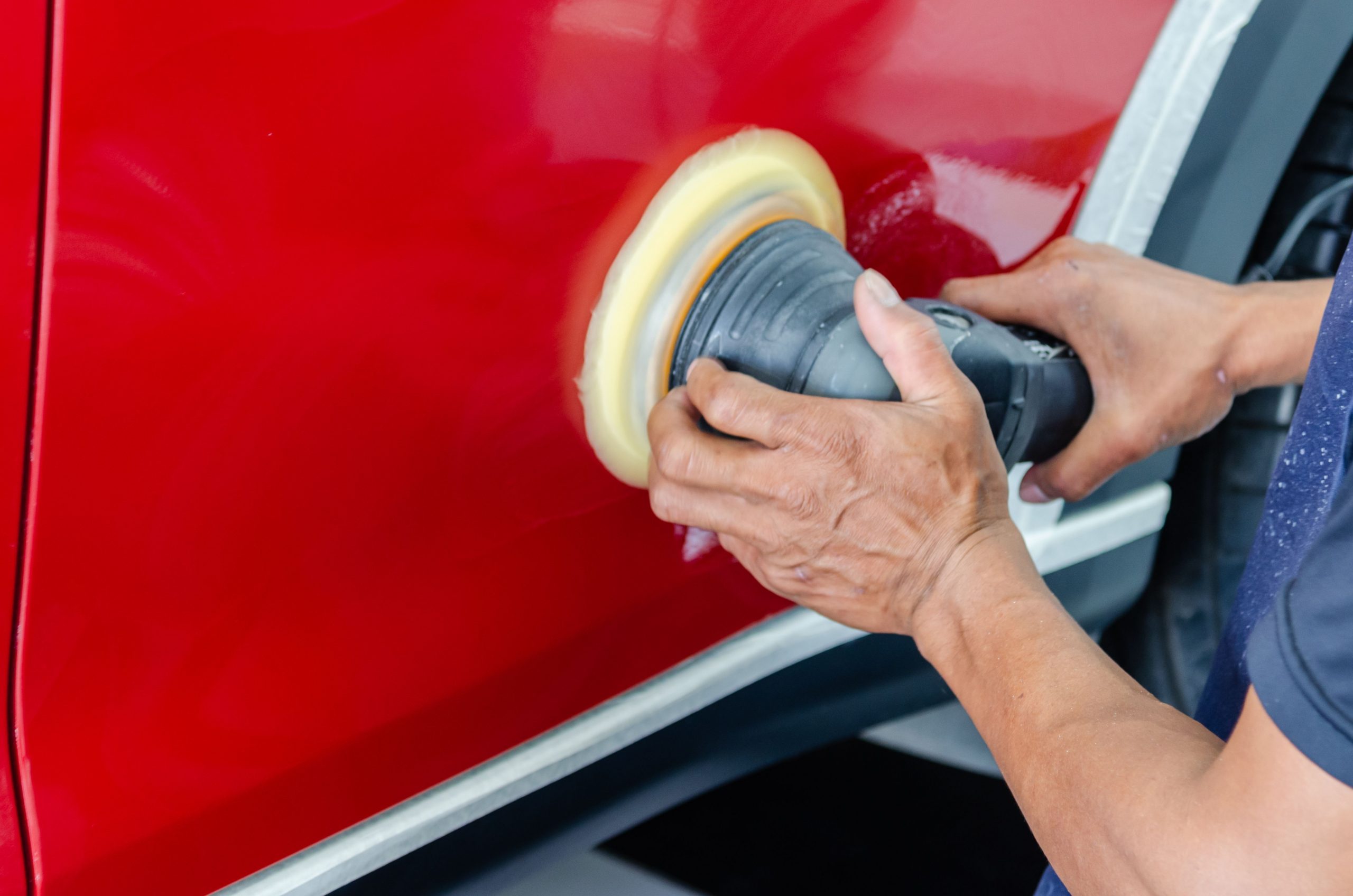 mechanic buffing a red car